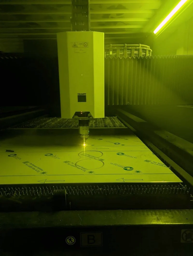 Faserlaser-Schneidkopf beim Laserzuschnitt einer Blechtafel mit Schutzfolie