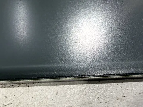 Anthrazit lackiertes Aluminiumblech mit Schutzfolie, gelaserte Kante mit deutlich abgeplatzter Farbbeschichtung
