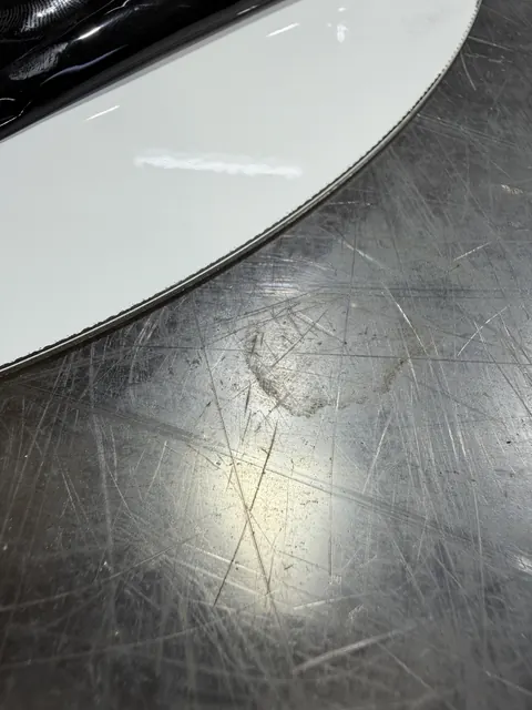 Weiß lackiertes Blech mit gelaserter runder Kante und dunklem Saum
